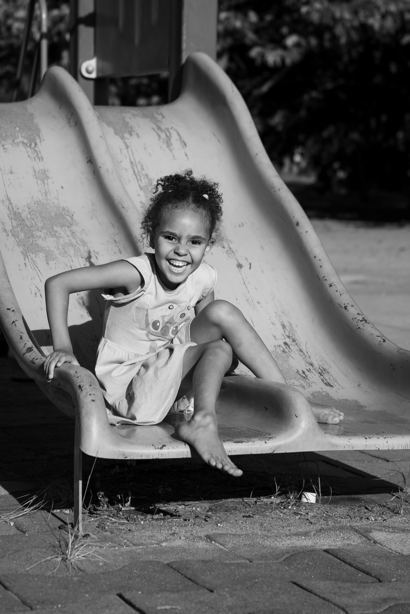 hero-img-02 A happy child playing on a playground slide captures pure joy in a black and white setting.