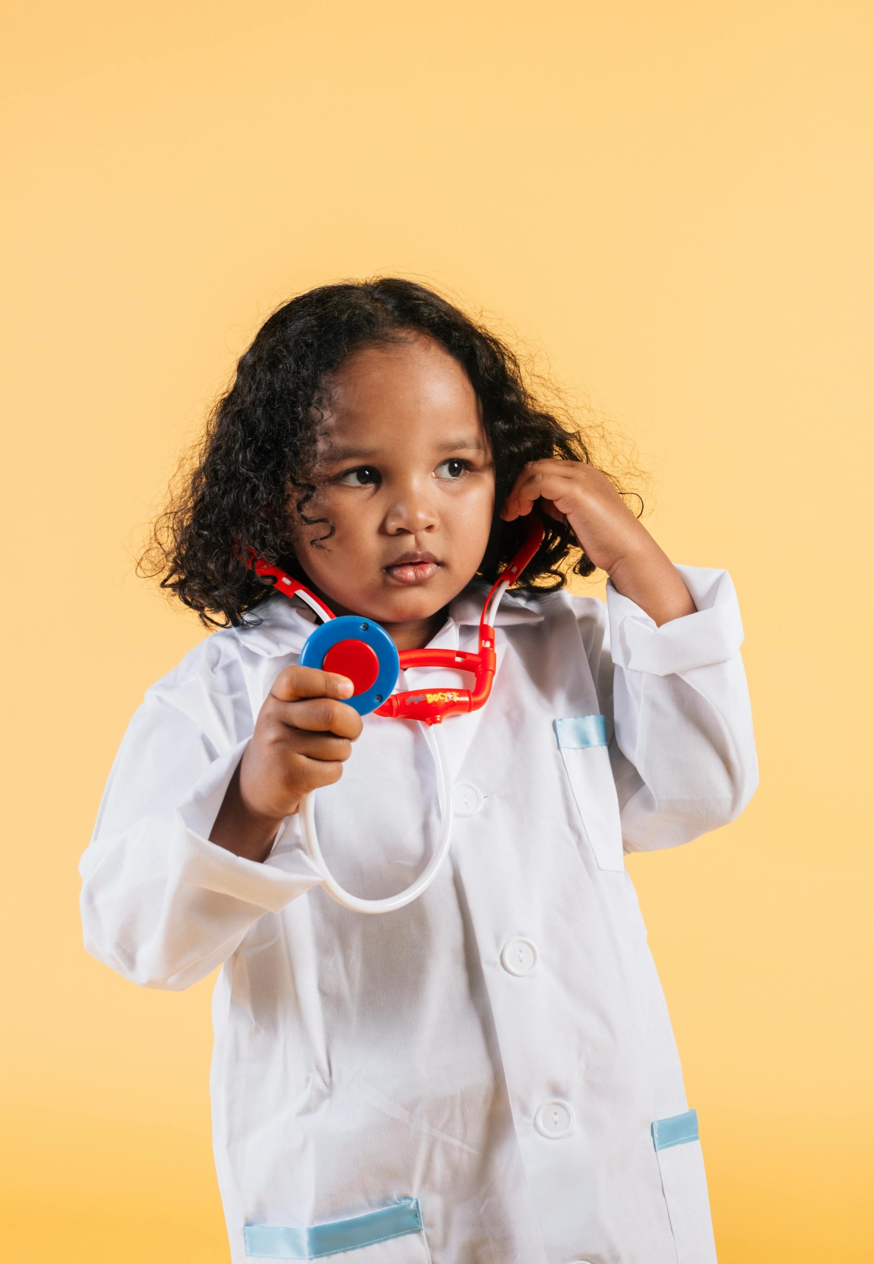 our-services-2 Cute child dressed as a doctor with a stethoscope against a yellow background.